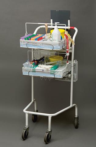 På hjul ind i medicinhistorien. En prøvetagningsvogn med reagensglas og farvede låg, en dunk sprit, plaster, vatkugler, swaps, staseslange samt en kanylebøtte.