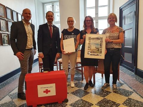 Fælledstillidsrepræsentanterne overrækker kufferten til Nicolai Wammen (2. tv).  Billede bragt med tilladelse fra Facebookgruppen "Sundhedsvæsenet - sammen er vi stærkest"